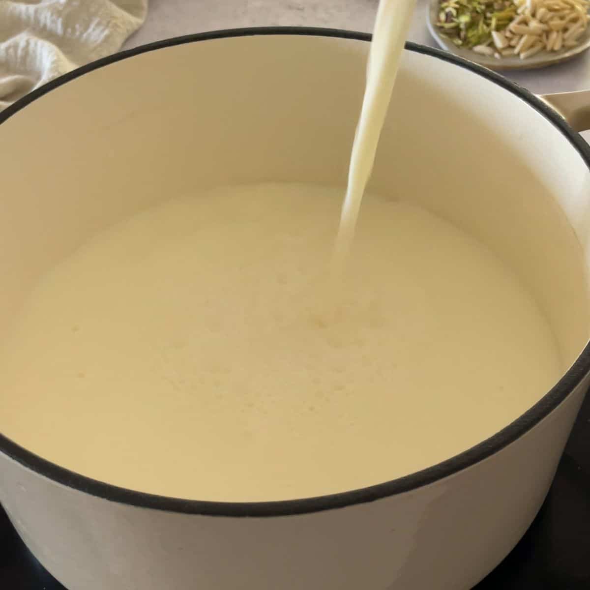 Milk being poured into a pot from above.