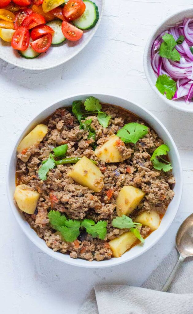 A bowl full of Pakistani keema aloo topped with coriander leaves.