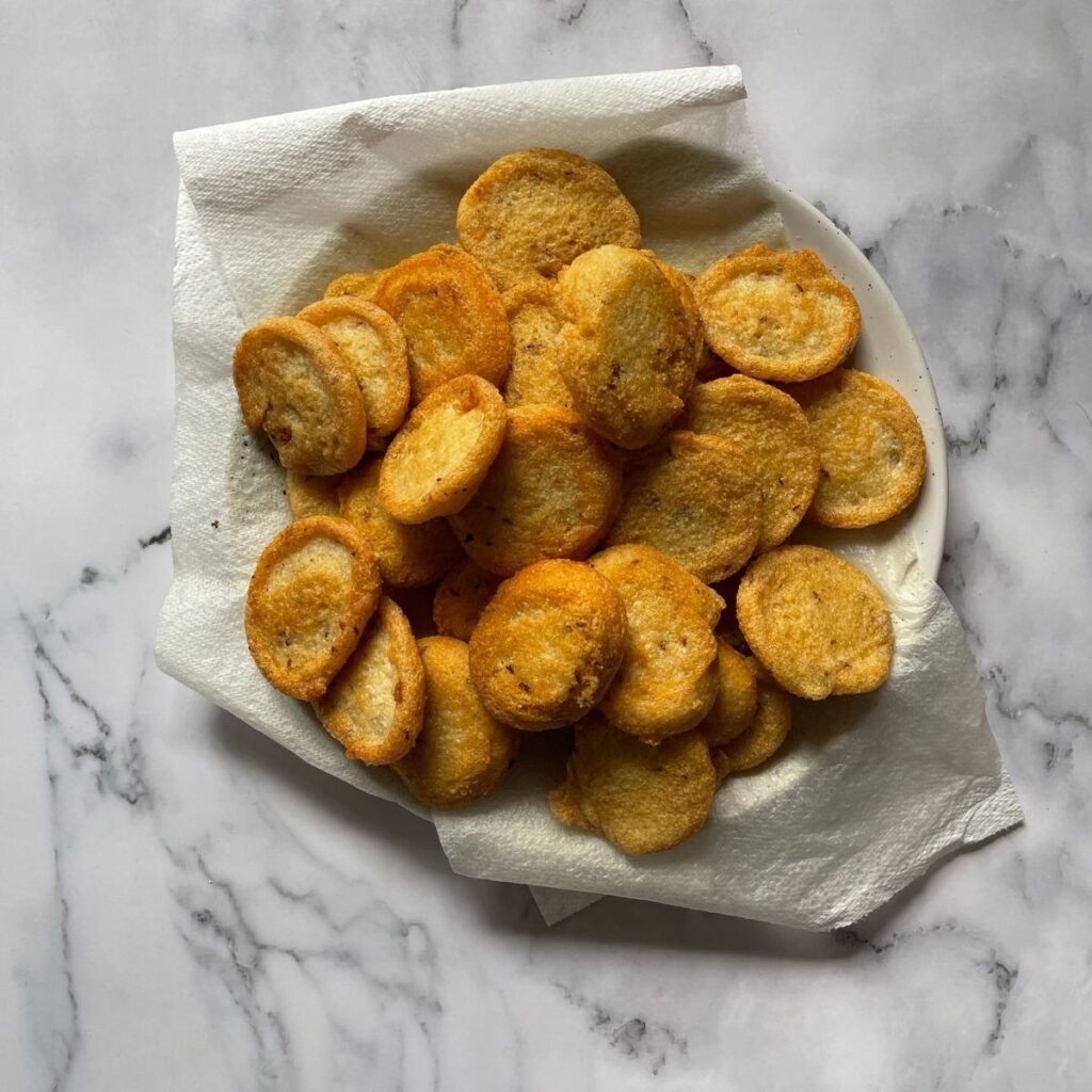 Fried lentil fritters or mash ki daal kay dahi baray in a plate lined with kitchen towel.