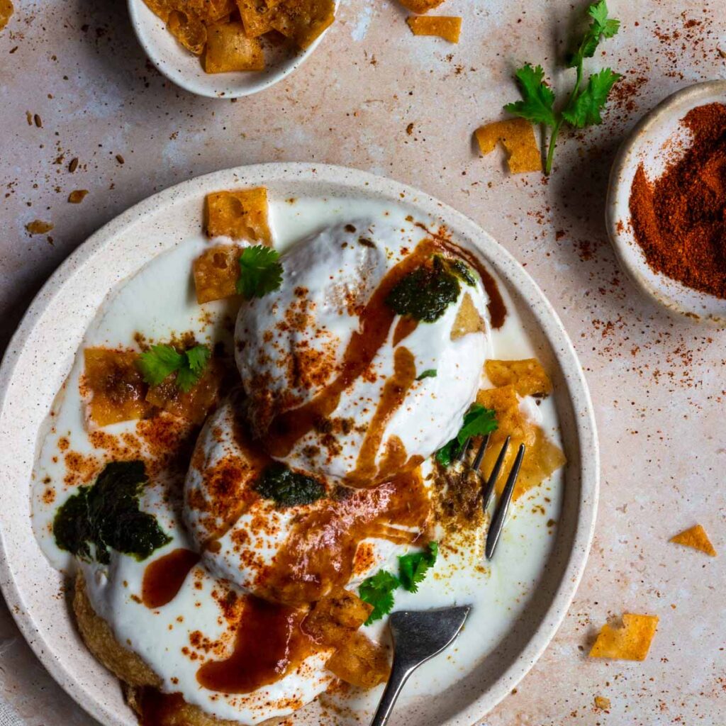 A plate of lentil fritters with yoghurt, with spices on the side.