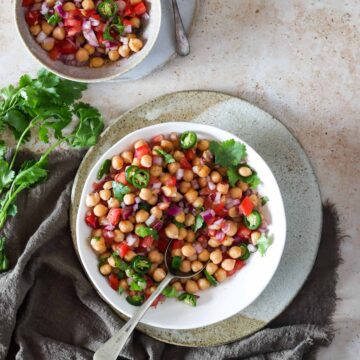 Two bowls of chana chaat, with one bowl having a spoon in it.