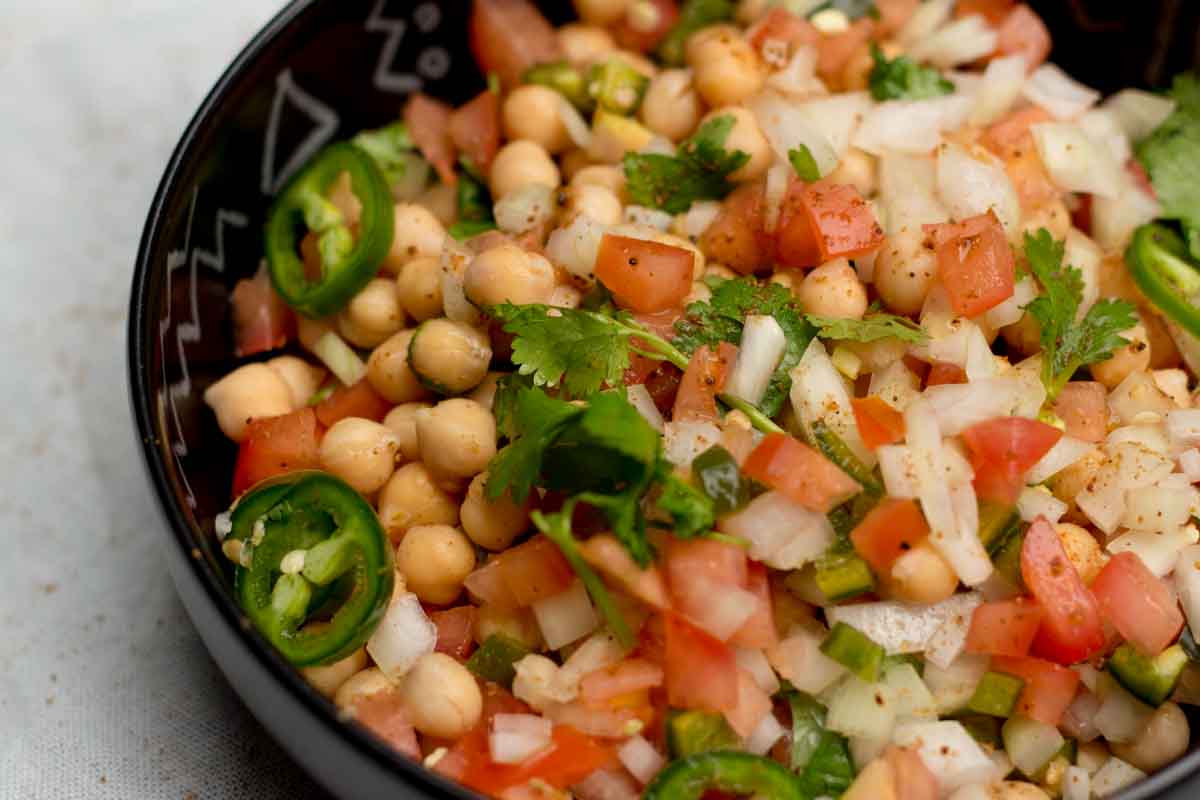 A bowl of chana chaat (chickpea chaat) topped with coriander leaves.