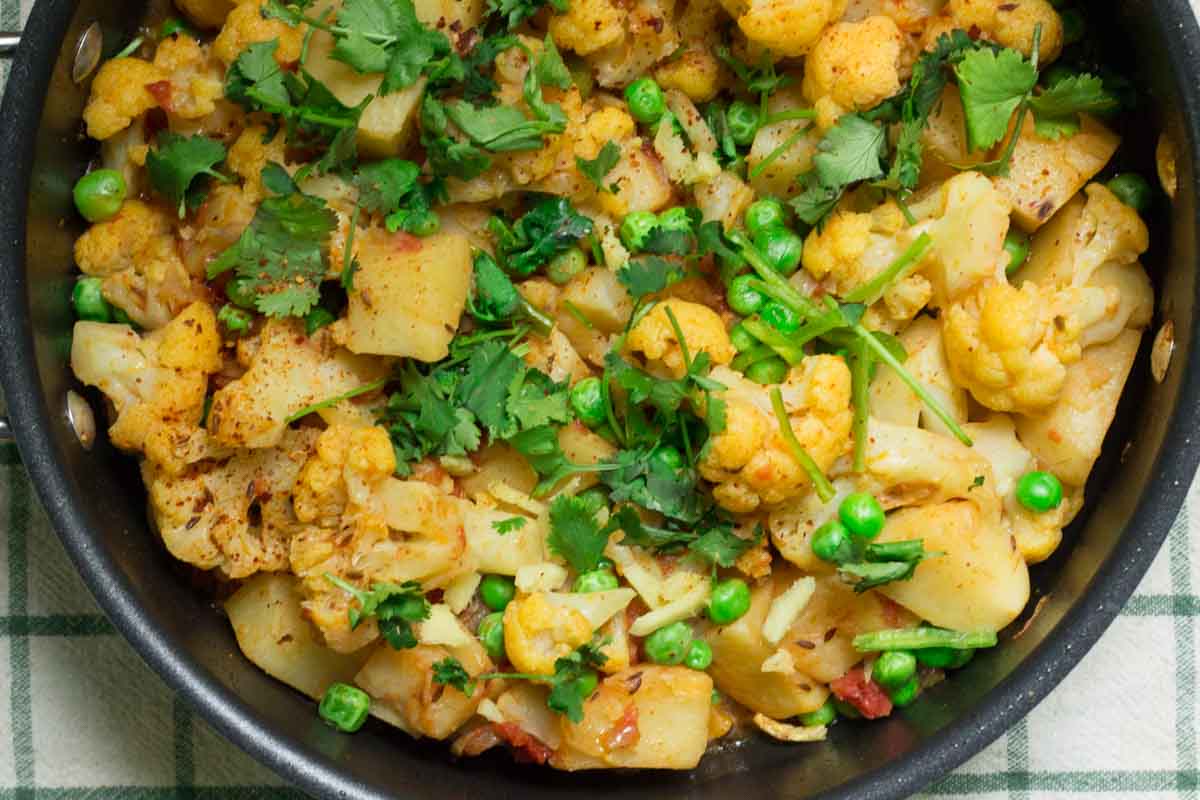 A dish filled with aloo gobi matar sabzi (potato, cauliflower and peas curry). 