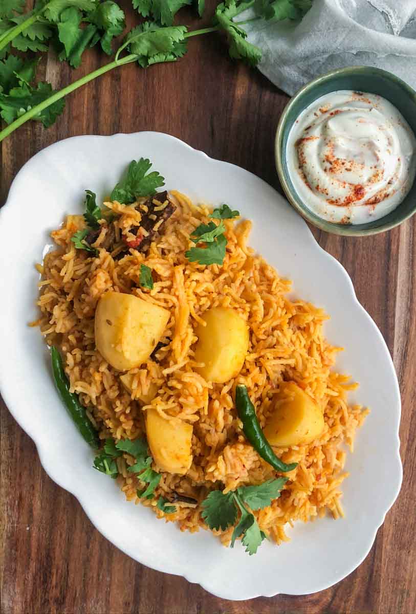 Aloo tahari (spiced potato rice) in a platter with raita on the side.