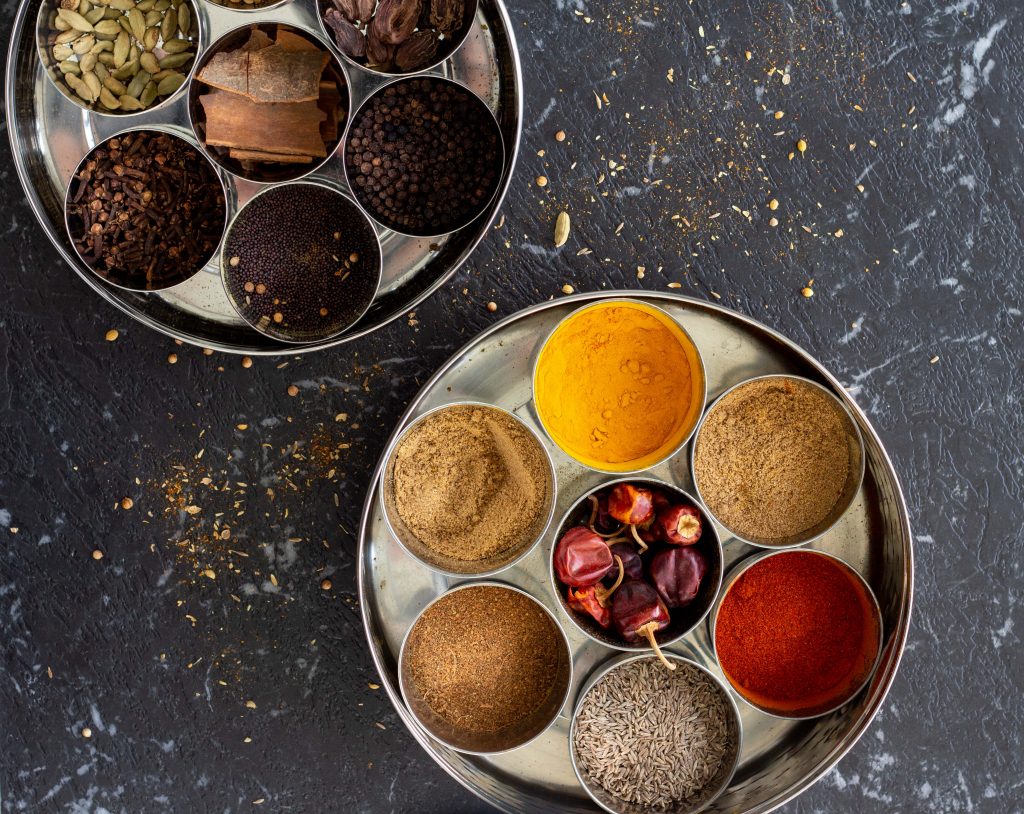 Two Indian masala dabbas (spice boxes) on a black background.