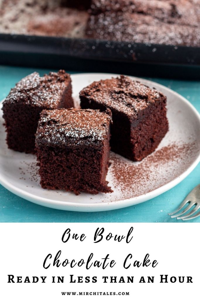 Three slices of one bowl chocolate cake on a white plate, and dusted with icing sugar and cocoa powder. On the back of the plate is a tray with chocolate cake in it. 