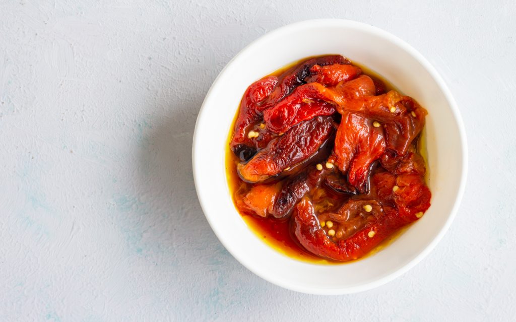 A bowl of roasted red peppers with oil. 