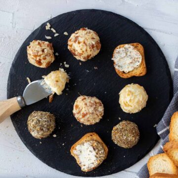 Assorted mini cheese balls set on a black slate platter.