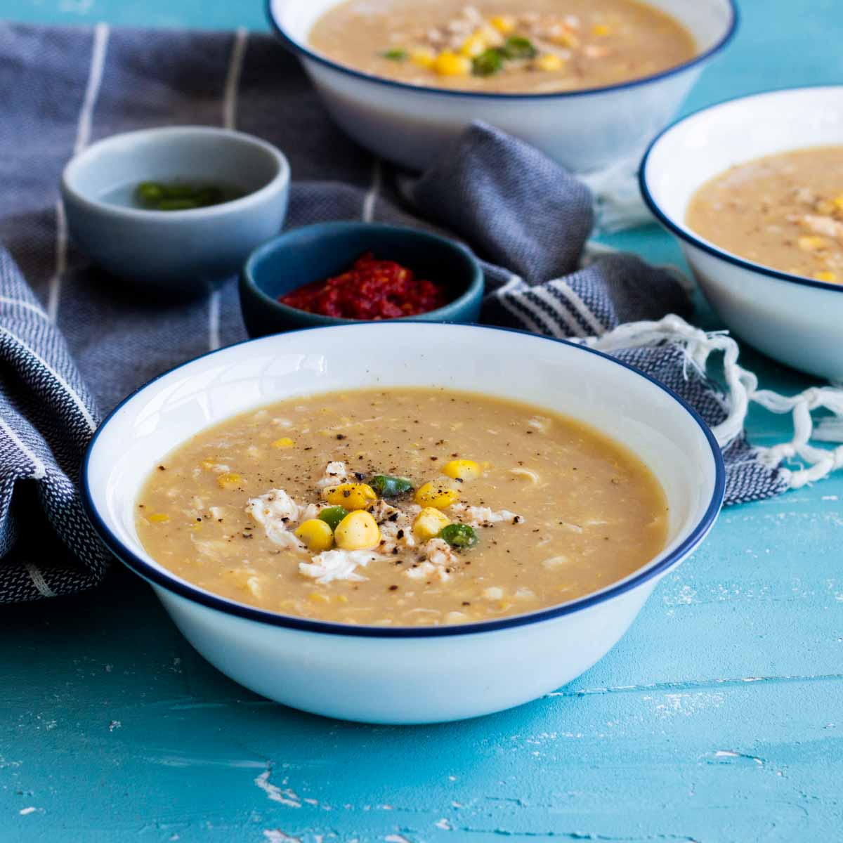 A bowl of Chinese chicken corn soup on a blue background.