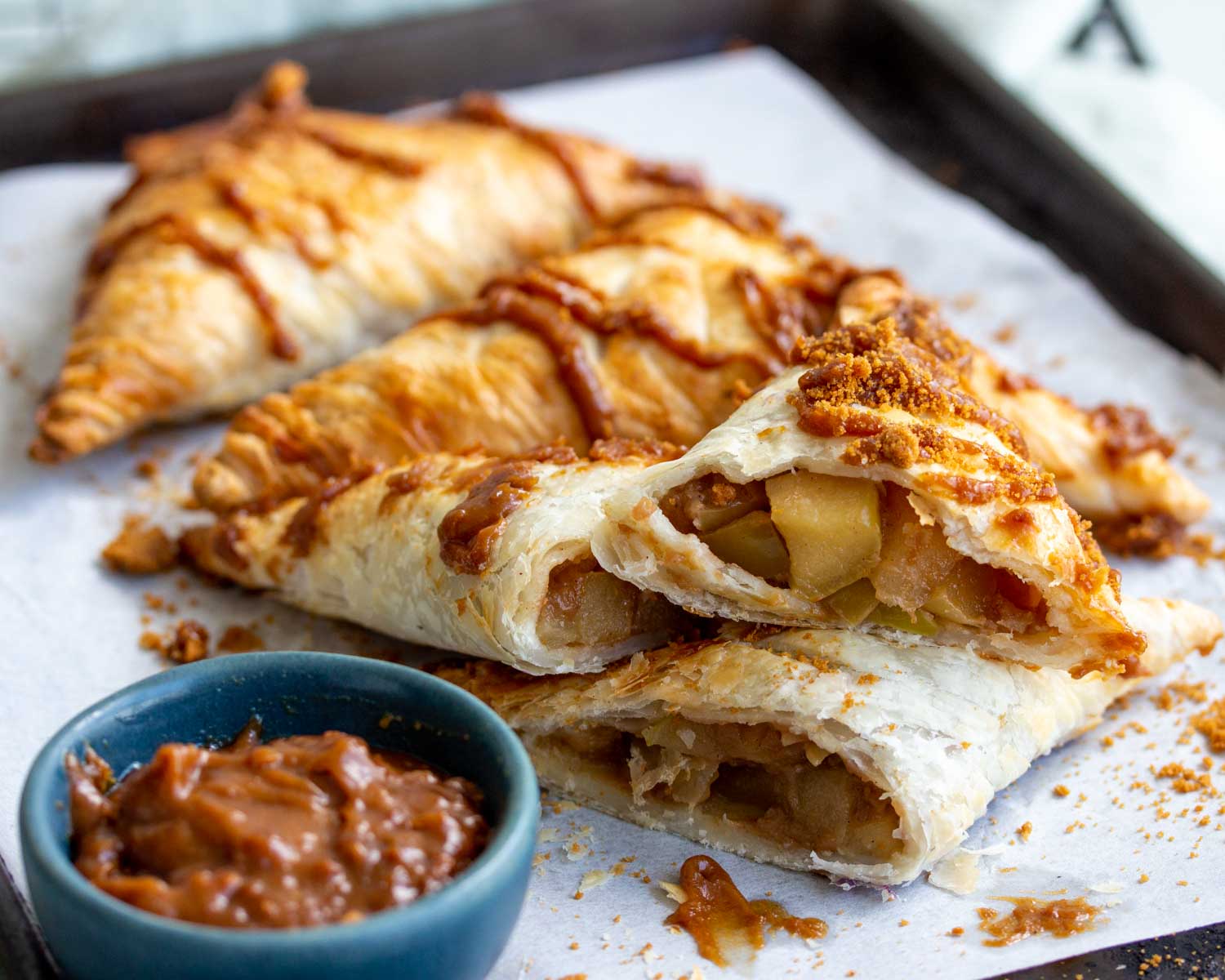 Four apple biscoff turnovers on a baking tray.