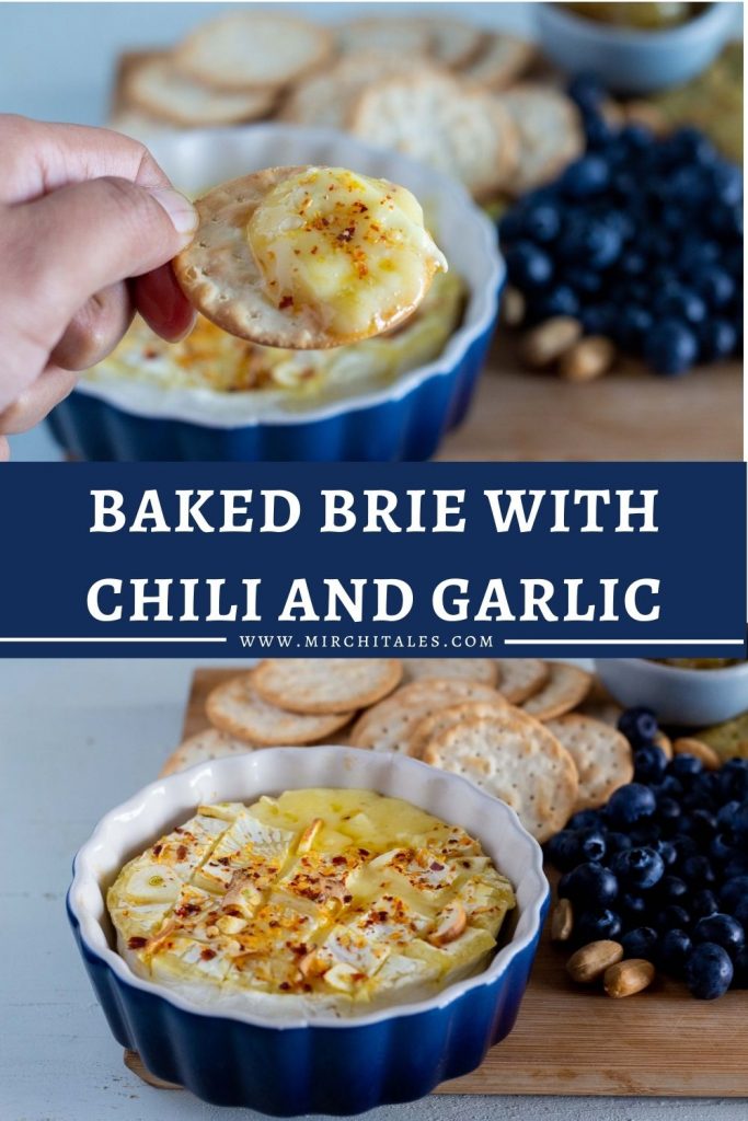 Baked brie with garlic and chili in a cheese board which has blueberries, crackers and nuts.