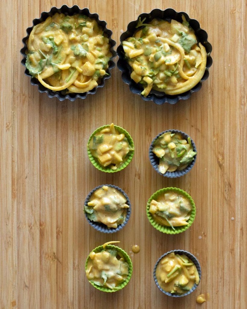 8 baking molds filled with air fryer pakora batter of chickpea flour, coriander, green chilies and onion. 