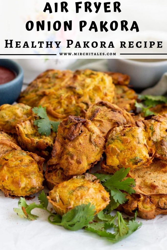 A mound of air fryer pakoras with coriander on top. Behind the air fryer pakoras is green chili sauce, and tomato ketchup.