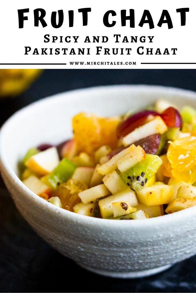 A bowl of fruit chaat containing diced apples, diced oranges, diced grapes, and diced kiwifruit in a white bowl on a white background.