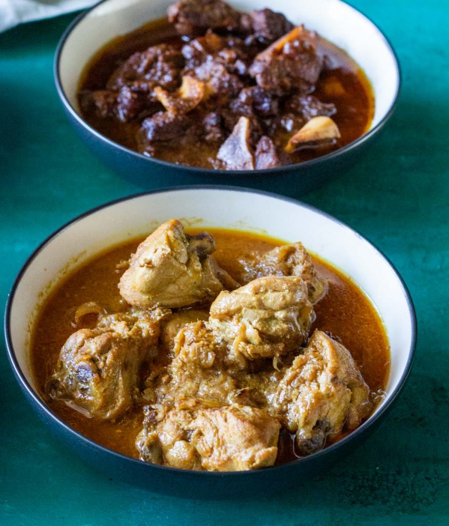 A bowl of bone in chicken curry (chicken ka salan). On the back of the bowl is a bowl of goat meat curry.