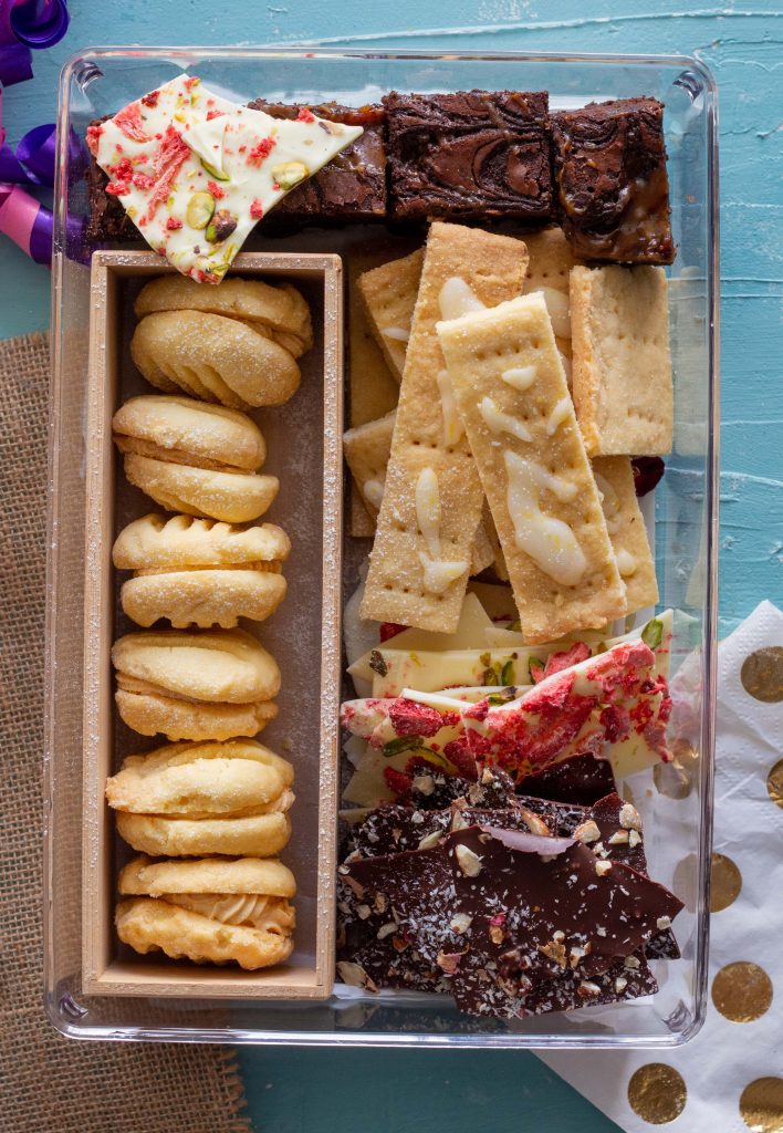 Eid cookie box featuring salted caramel melting moments, chocolate caramel brownies, lemon and cardamom shortbread, along with dark chocolate and white chocolate bark. 