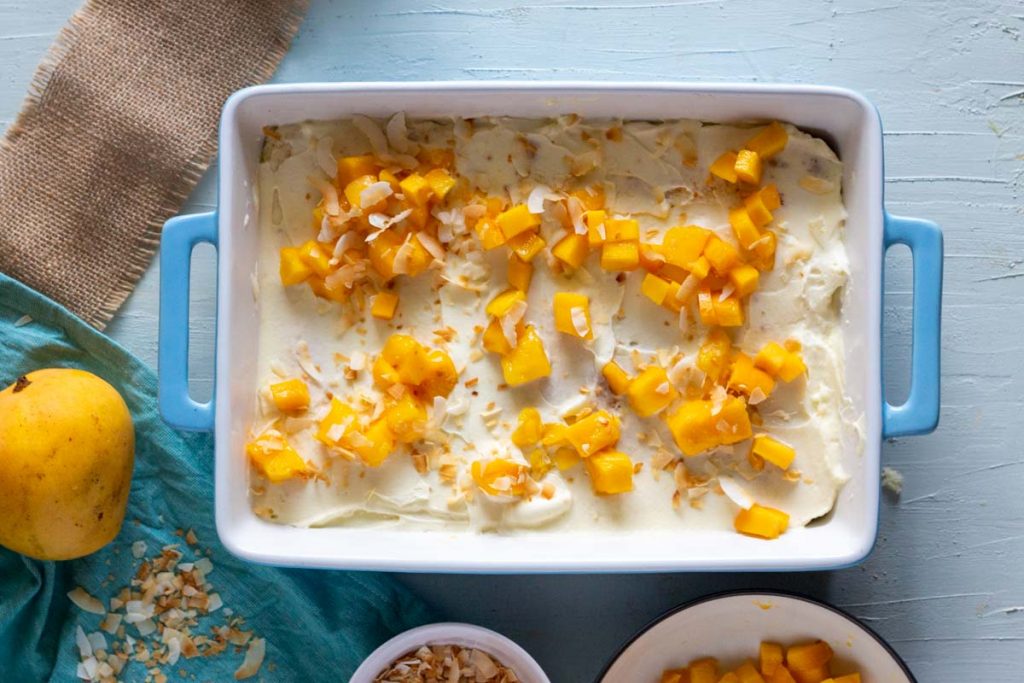 Mango coconut trifle or mango coconut layered dessert in a blue dish.