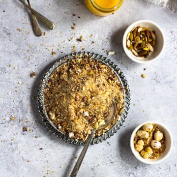 A bowl of panjeeri with nuts, seeds and ghee around it.